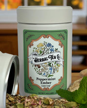 Herbal tea canister with a decorative label on a wooden surface with herbs.