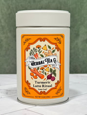 “Front of Turmeric Latte Ritual loose-leaf tea tin with an orange illustrated ingredient label.”