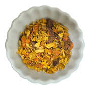 “Overhead view of Turmeric Latte Ritual loose-leaf herbal blend in a white scalloped bowl.”
