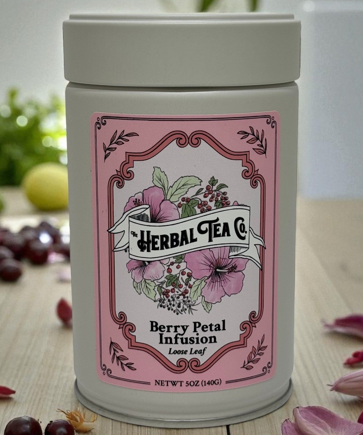 Herbal tea canister with pink label on a wooden surface with berries and flowers.