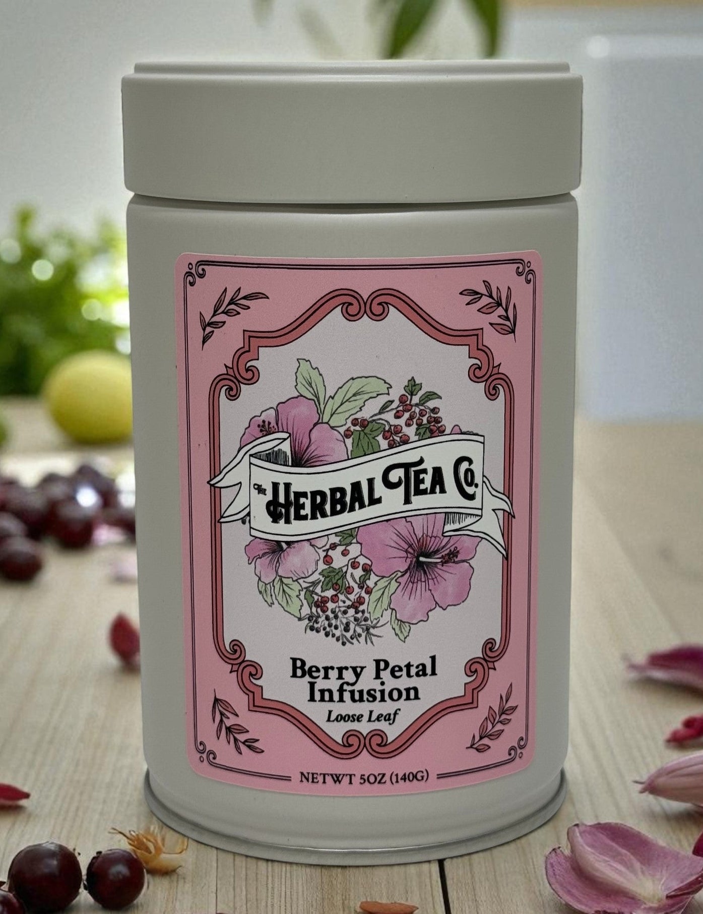 Herbal tea canister with pink label on a wooden surface with berries and flowers.