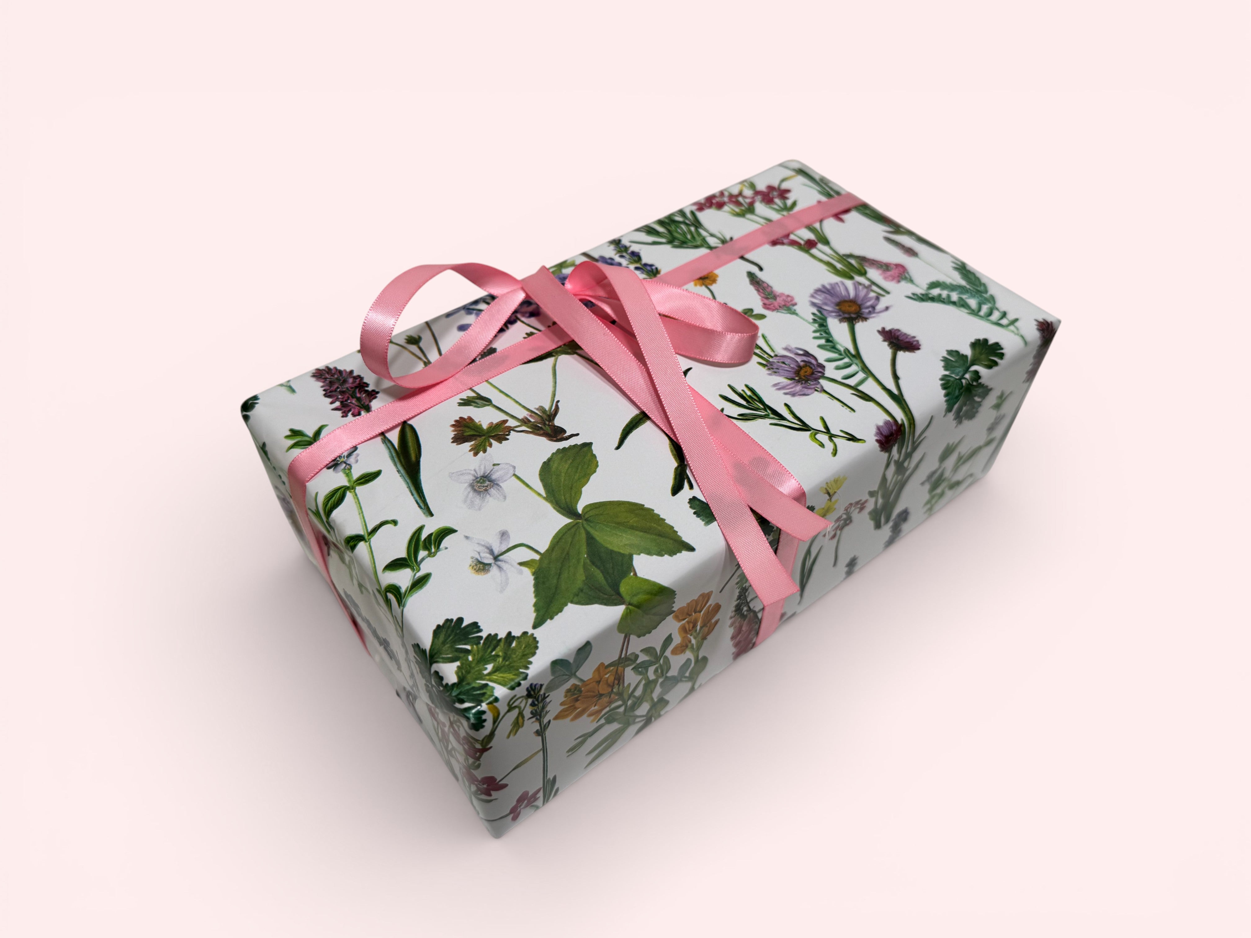 Gift box with floral pattern and pink ribbon on a white background