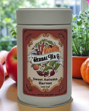 Tea canister with 'Herbal Tea Co' label on a table with apples and pumpkins